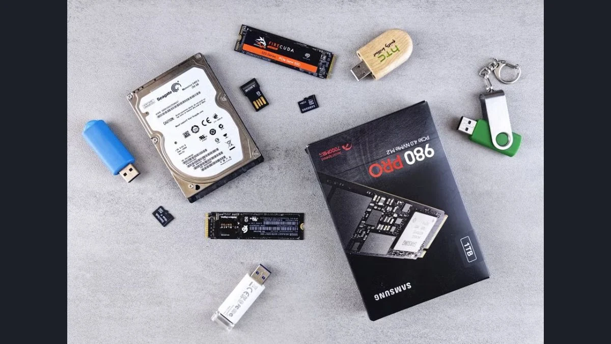 Overhead view of various PC storage hardware, including a boxed Samsung 980 Pro NVMe M.2 SSD, hard drives, and flash memory sticks.