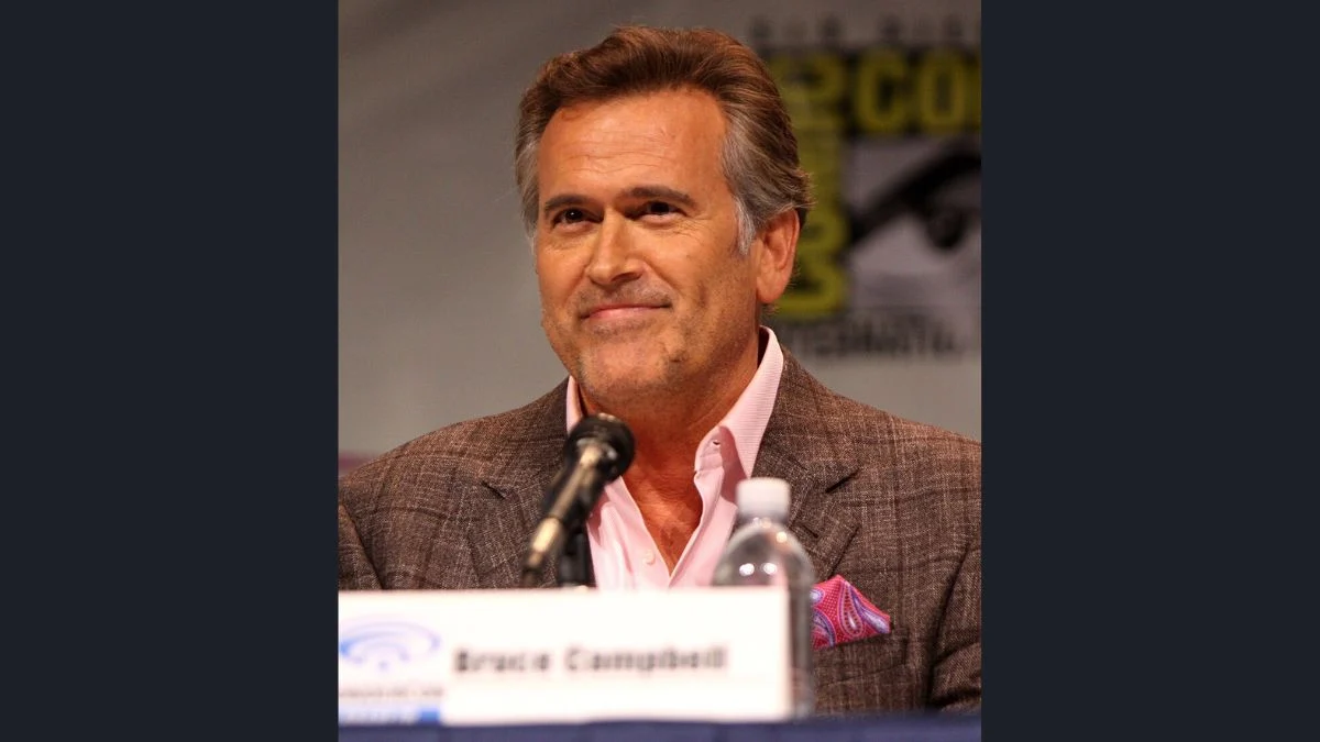 Actor Bruce Campbell smiling at a panel microphone while speaking about his career and health update.