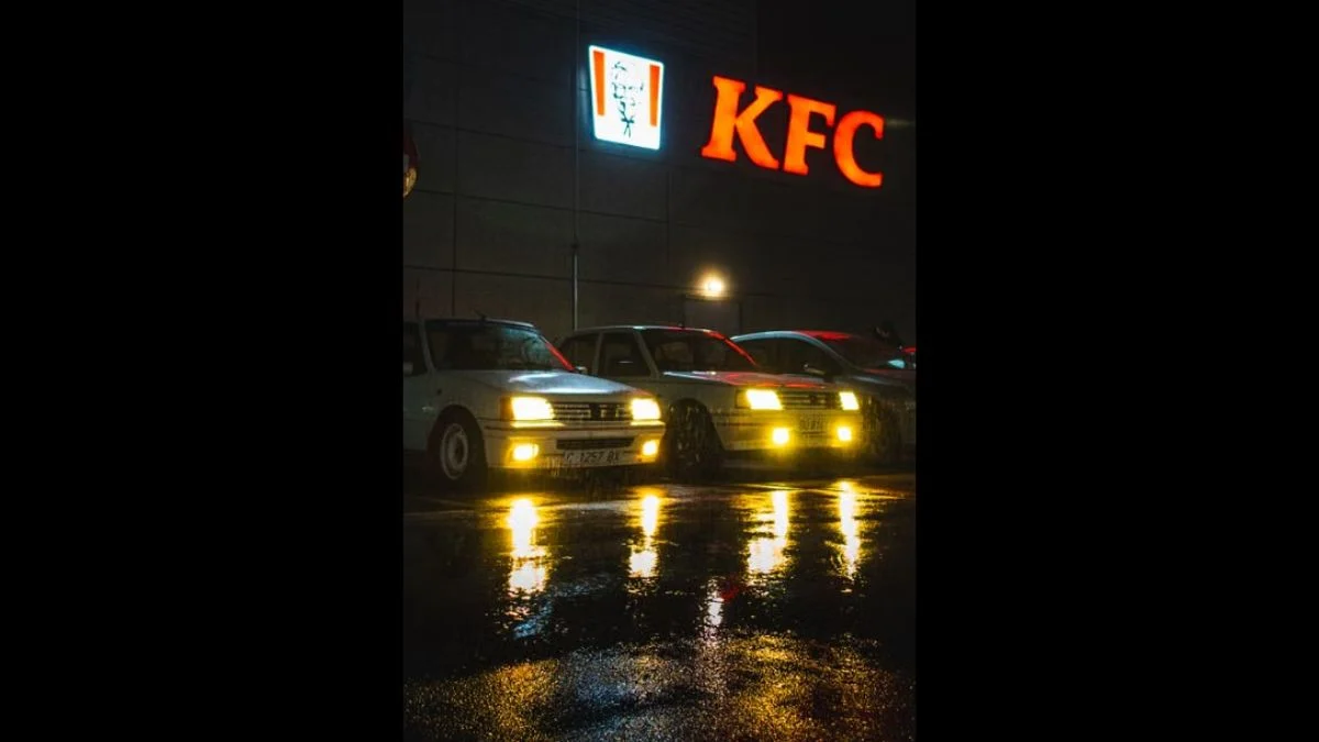 Illuminated KFC restaurant sign glowing above a car park at night