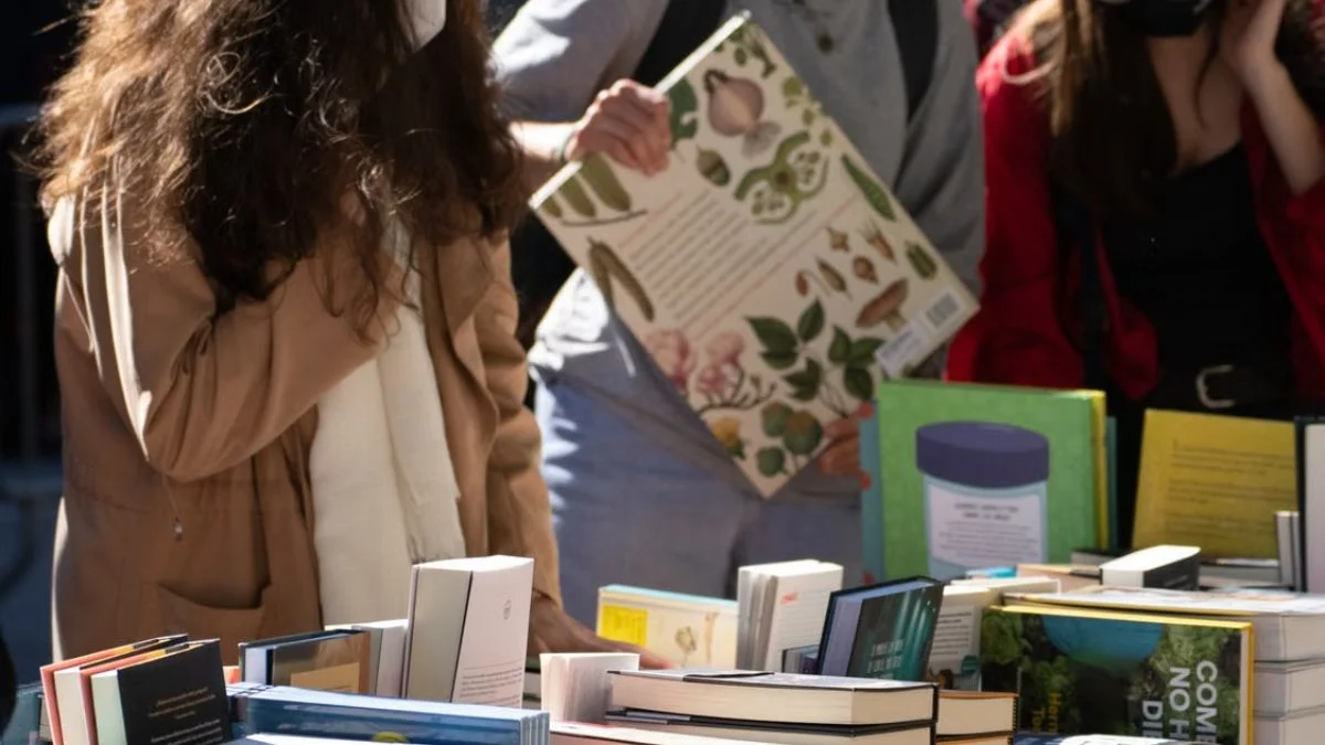 Readers browsing books displayed on tables at an outdoor book festival.