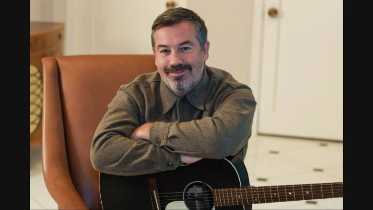 Musical theater composer and singer-songwriter Duncan Sheik smiling with an acoustic guitar