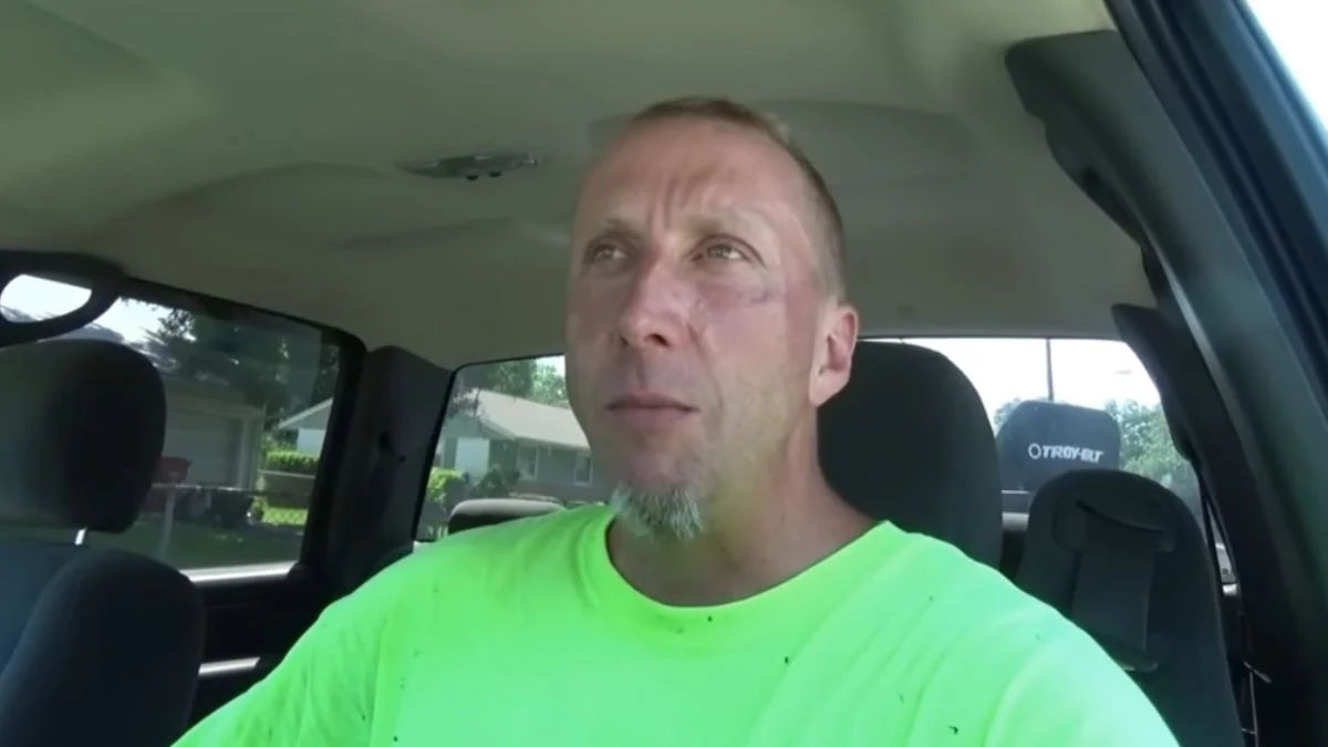 Greg Chism sitting inside a truck wearing a high-visibility neon shirt during his early lawn care YouTube days.