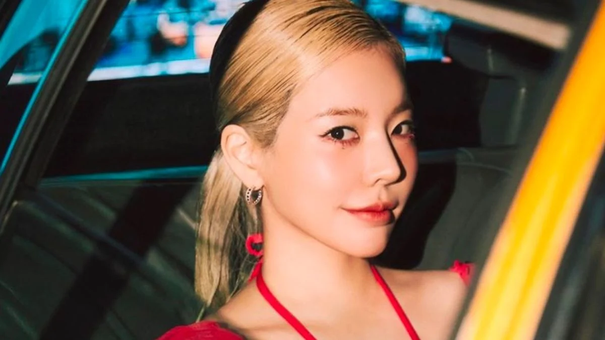 Girls' Generation member Sunny with blonde hair looking towards the camera inside a vehicle