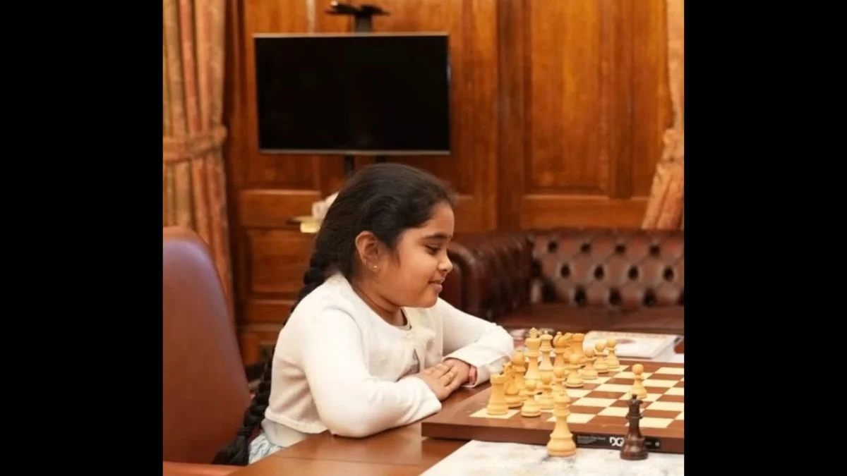 Young chess player Bodhana Sivanandan concentrating over a chessboard at a wooden table.