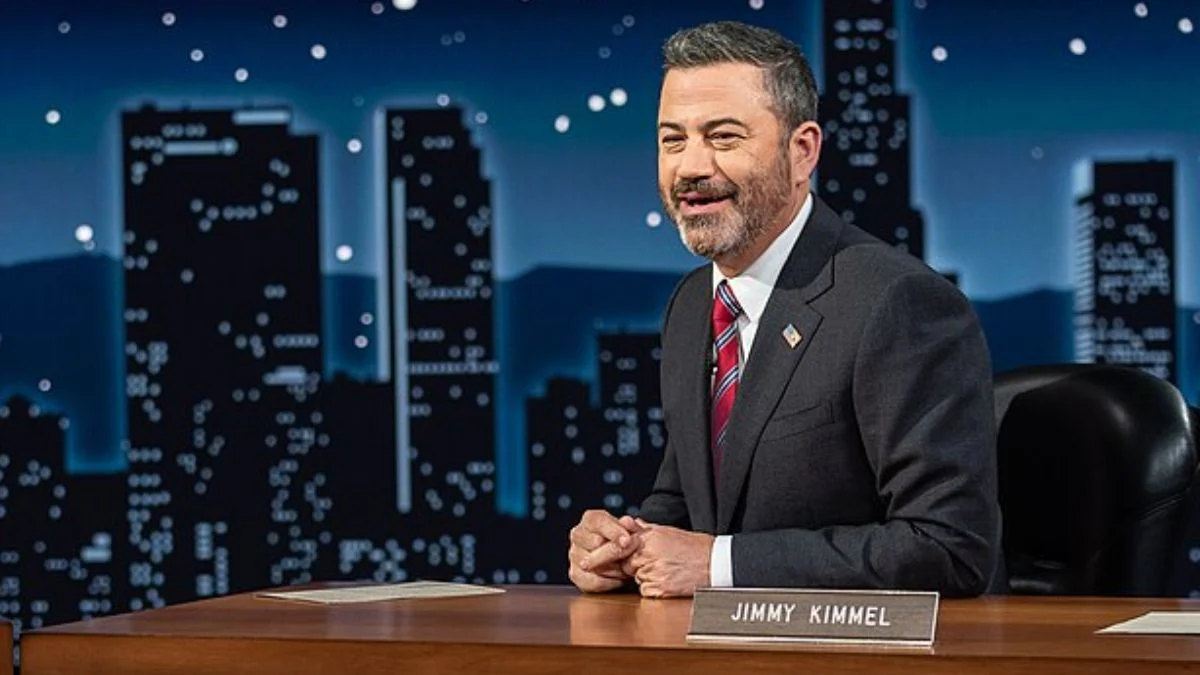 Jimmy Kimmel smiling at his late-night desk on the set of Jimmy Kimmel Live.