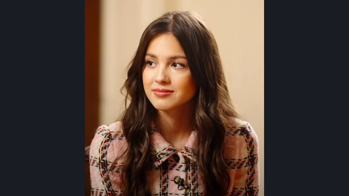 Olivia Rodrigo wearing a patterned pink tweed jacket sitting for a White House interview.