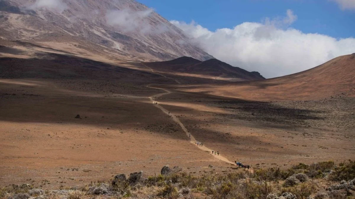 Wide shot of a barren dirt trail winding through a dry, mountainous African landscape.