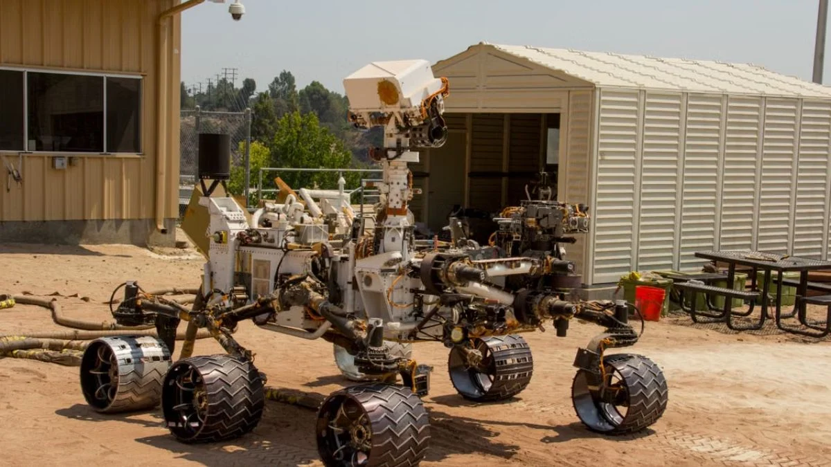 Mars rover prototype undergoing ground testing outdoors on a sandy surface.
