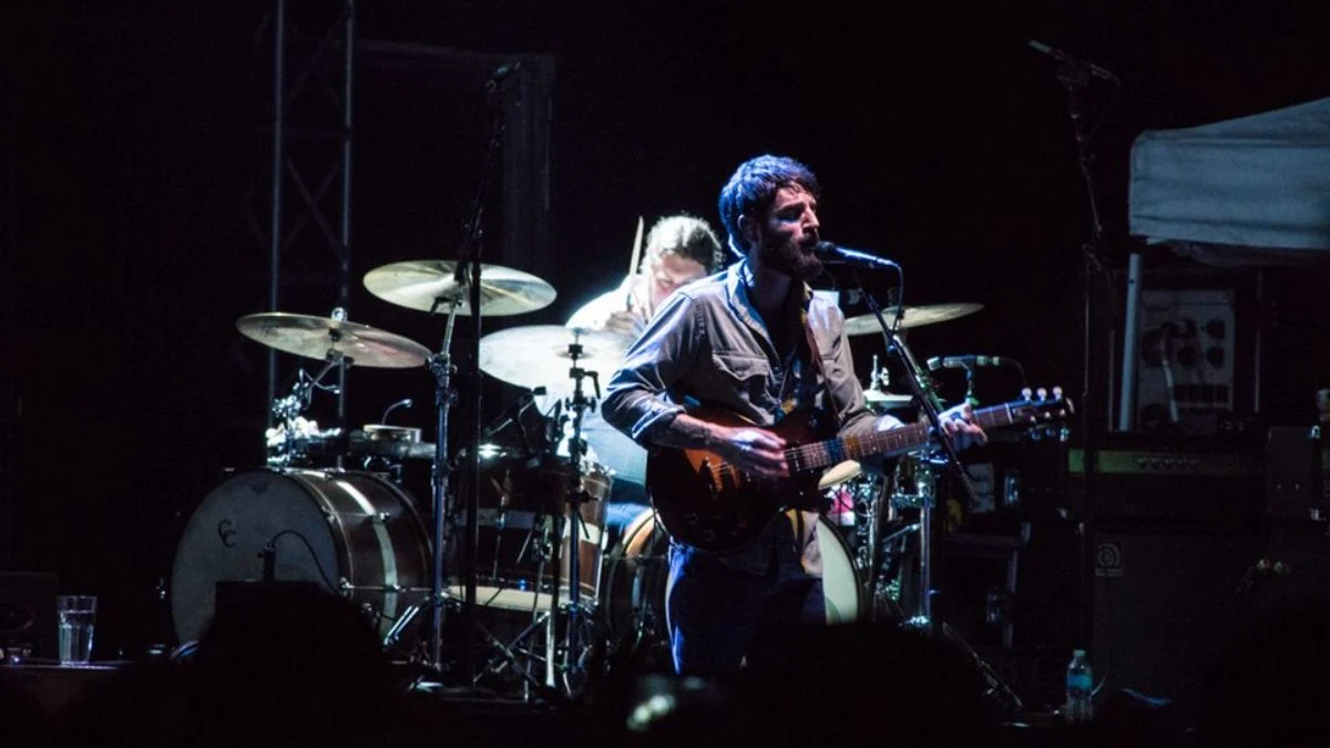 Singer-songwriter Ray LaMontagne performing live onstage with an electric guitar alongside a drummer under stage lighting.
