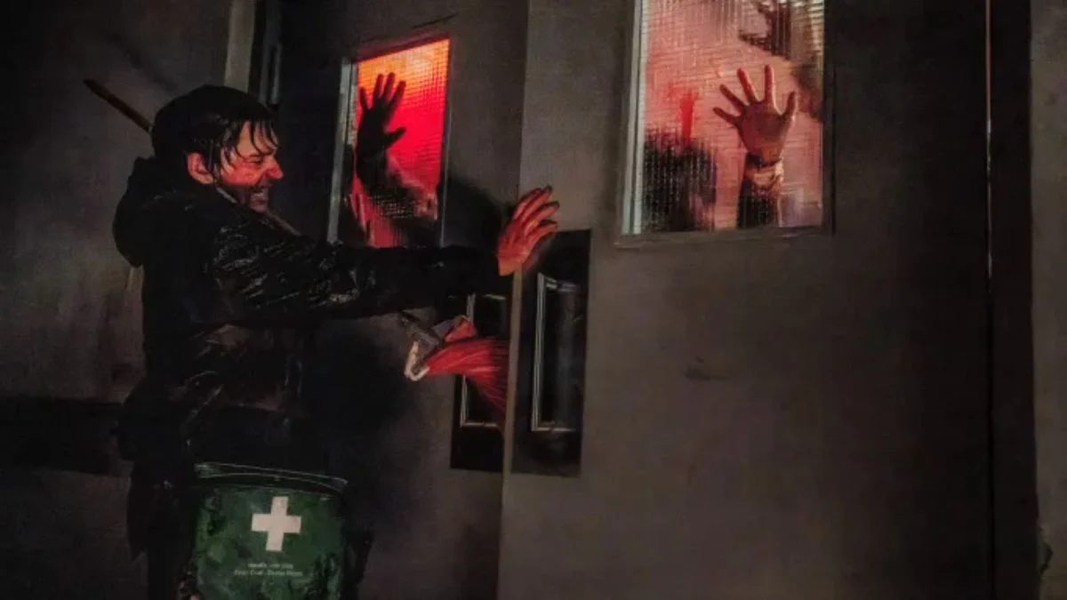 A man struggling against bloody hands reaching through glass doors in Zach Cregger's Resident Evil reboot
