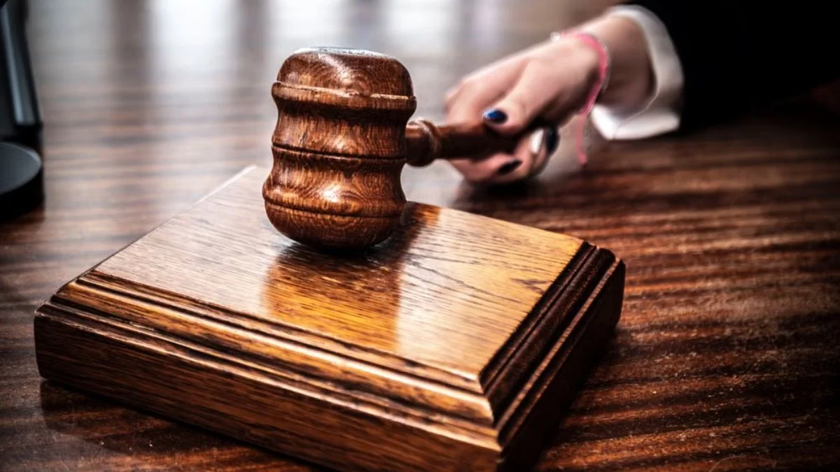 Close-up of a wooden judge's gavel sitting on a sound block on a court bench.