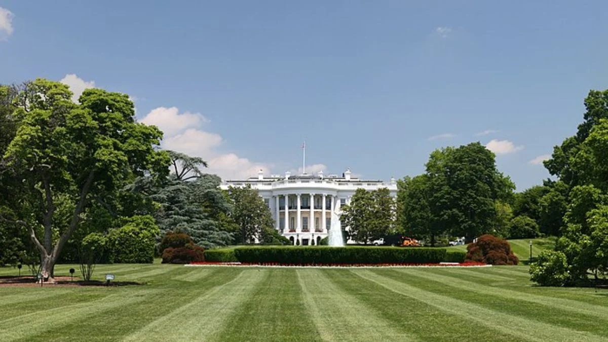 Exterior view of the White House building behind the green lawn and fountain