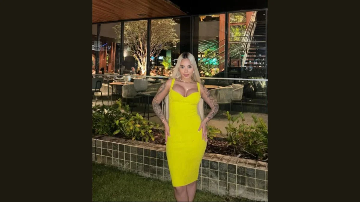 Evelyn Lima Dantas wearing a bright yellow dress in front of a modern glass building.