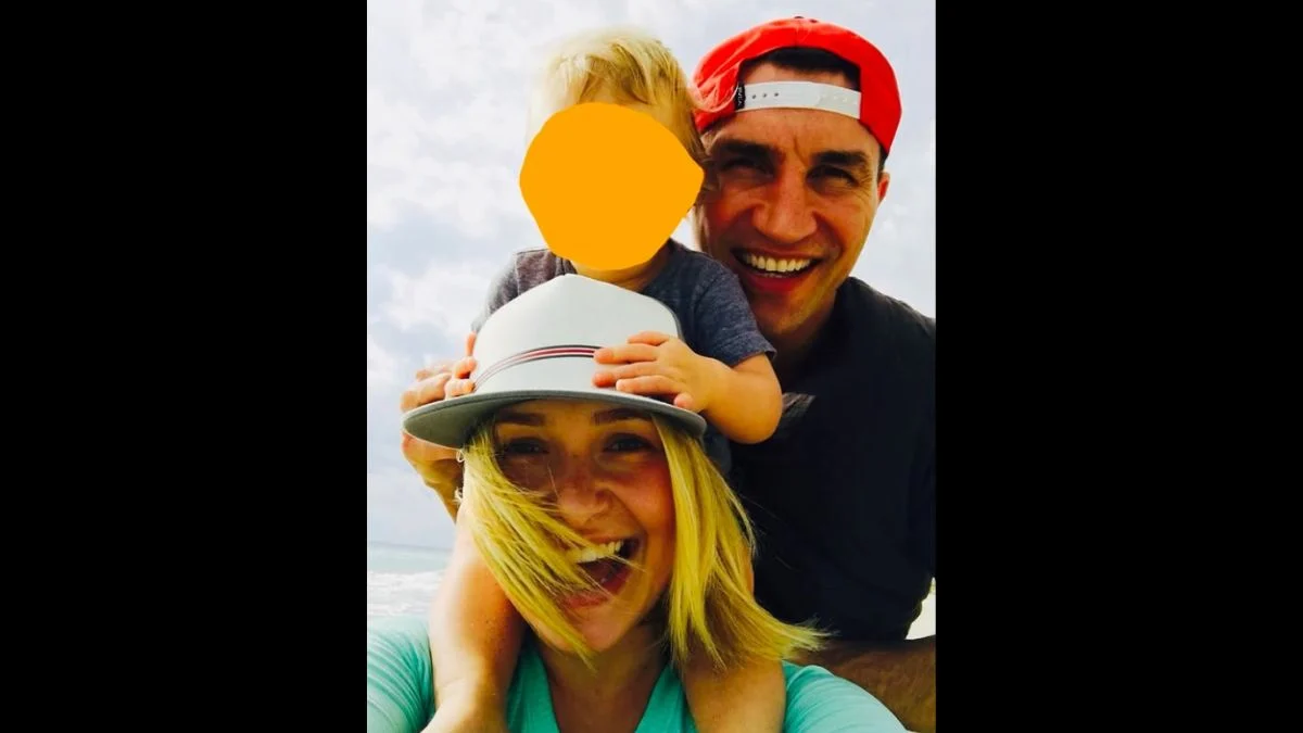 Wladimir Klitschko and Hayden Panettiere smiling with their young daughter Kaya outdoors.