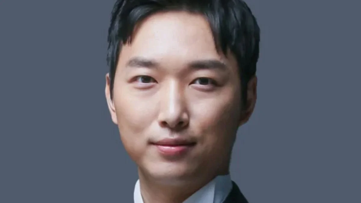 South Korean intellectual YoungHoon Kim smiling in a dark suit against a grey backdrop