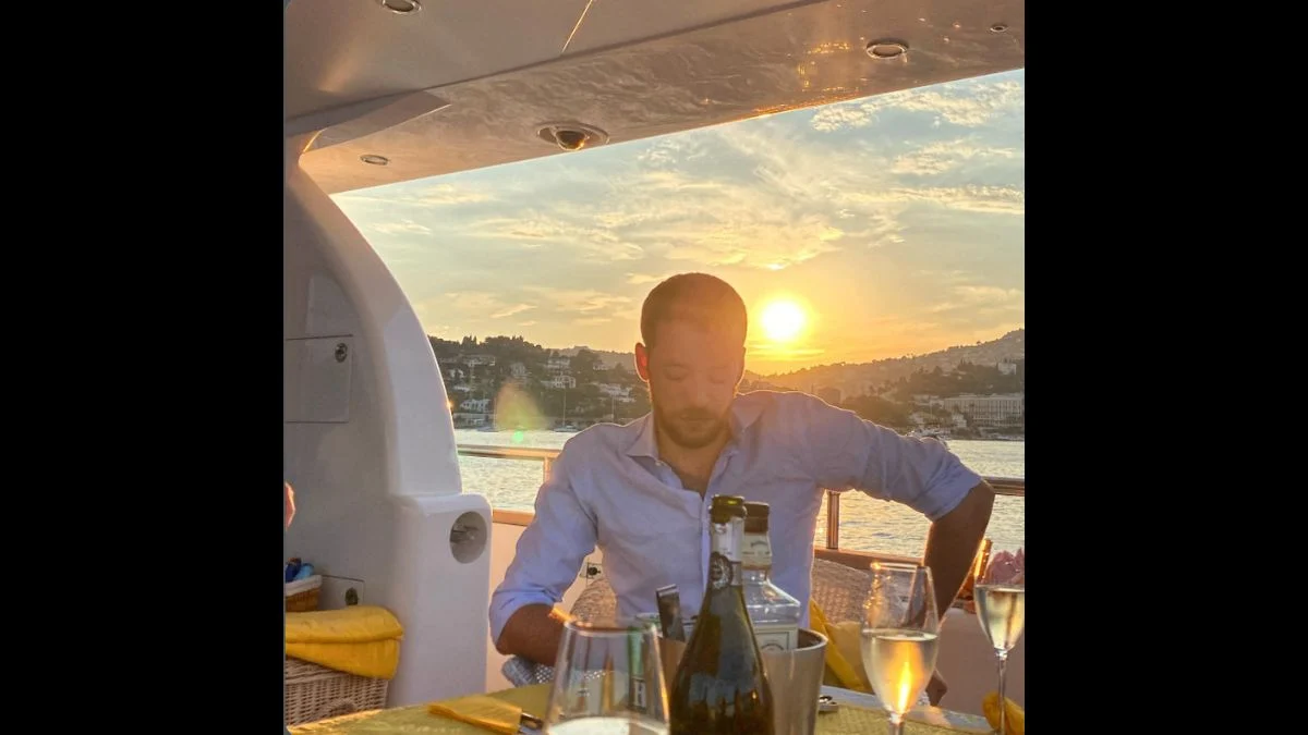 Antoine de Massy sitting at a table on a yacht at sunset