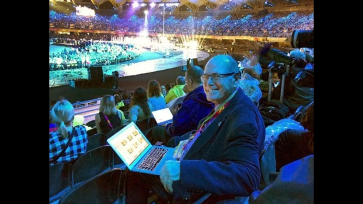 Royal photographer Arthur Edwards smiling with a laptop in stadium seating during a major event