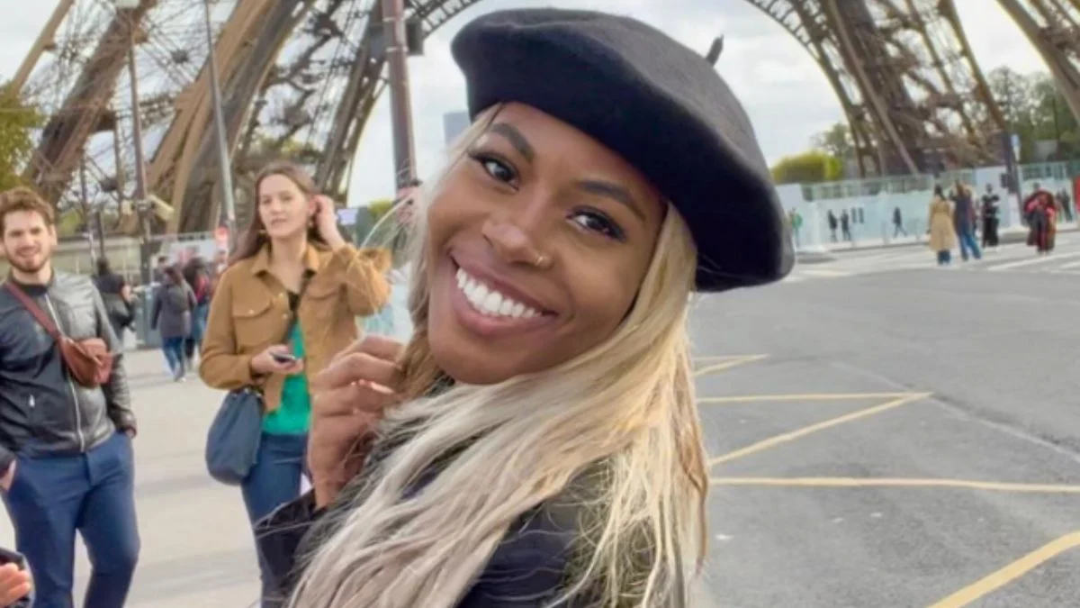 Anika Rashaun wearing a black beret and smiling outdoors near the Eiffel Tower in Paris