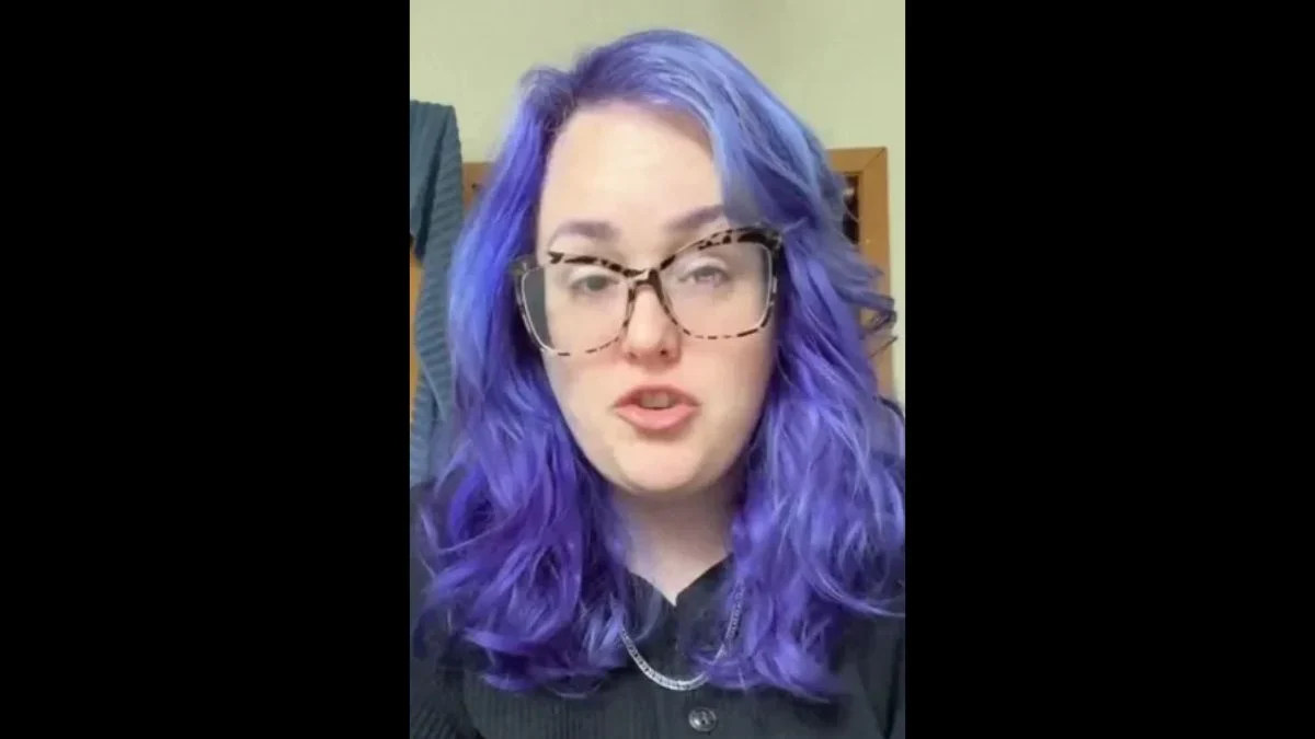 TikTok creator Tessa Dattillo speaking with purple hair and glasses in a video screenshot