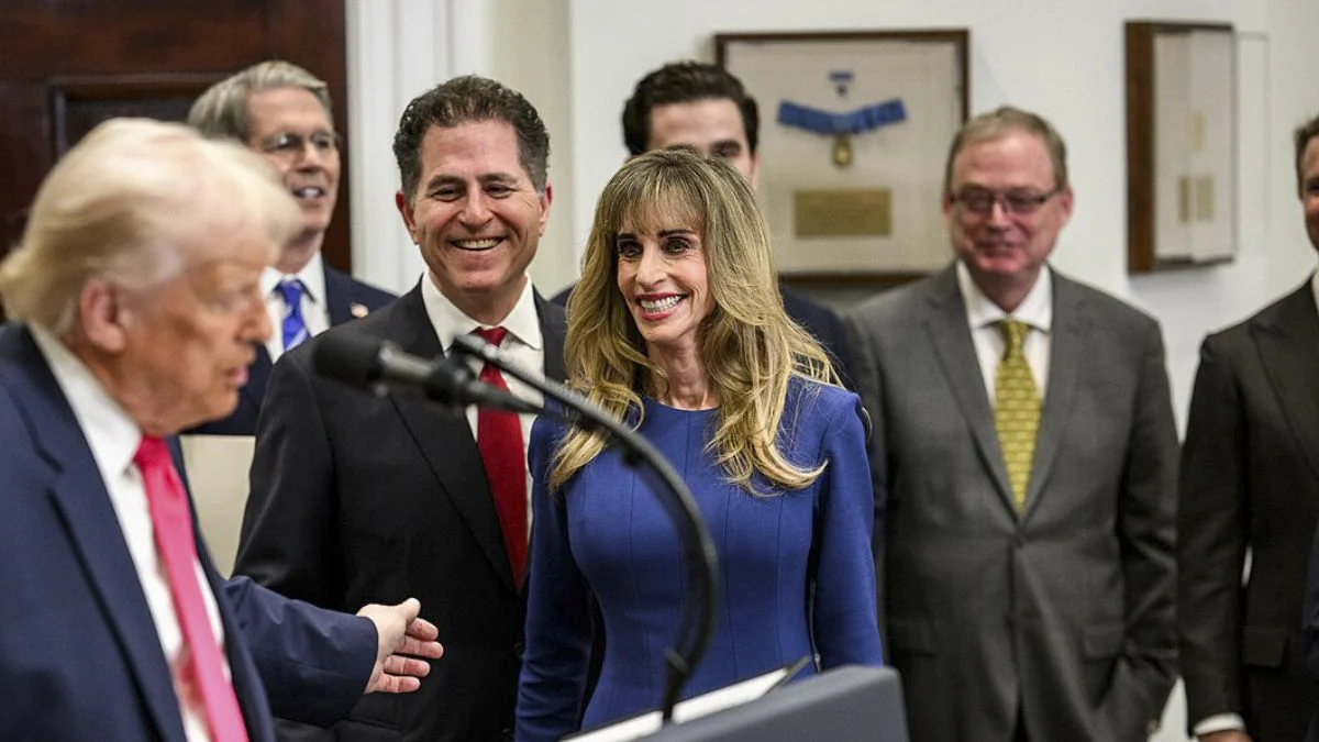Susan Dell in a blue dress smiling at a White House event alongside her husband Michael Dell and President Donald Trump.