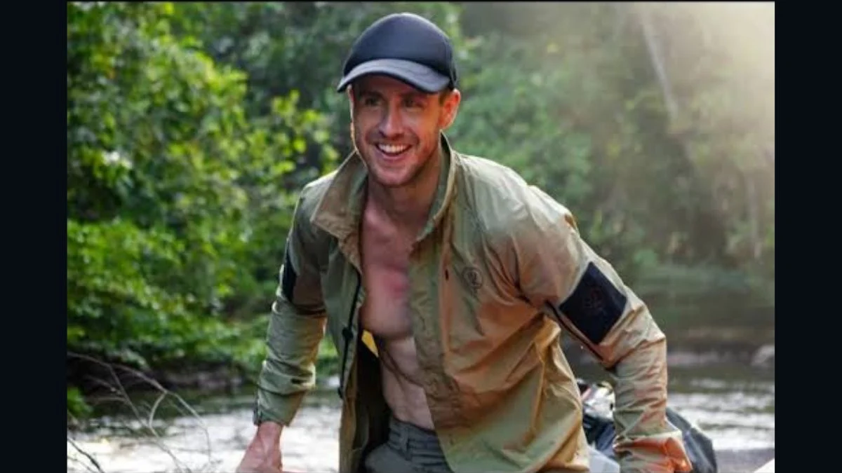 Welsh explorer Ash Dykes smiling in a cap and open jacket during a wilderness expedition along a river in a tropical forest.