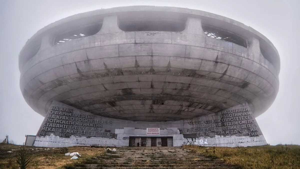 Large round brutalist concrete structure with saucer-like architecture shrouded in fog.