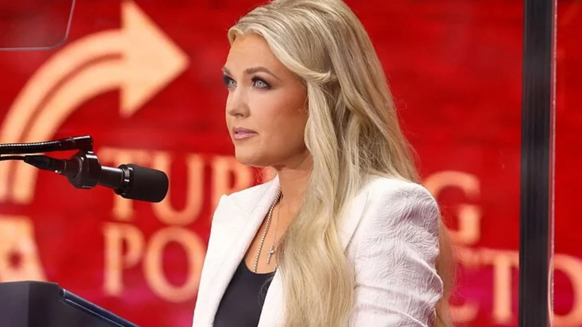Erika Kirk speaking at a podium wearing a white jacket