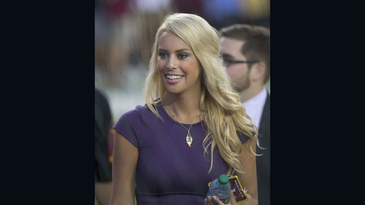 Britt McHenry smiling while holding a water bottle with a media credential around her neck