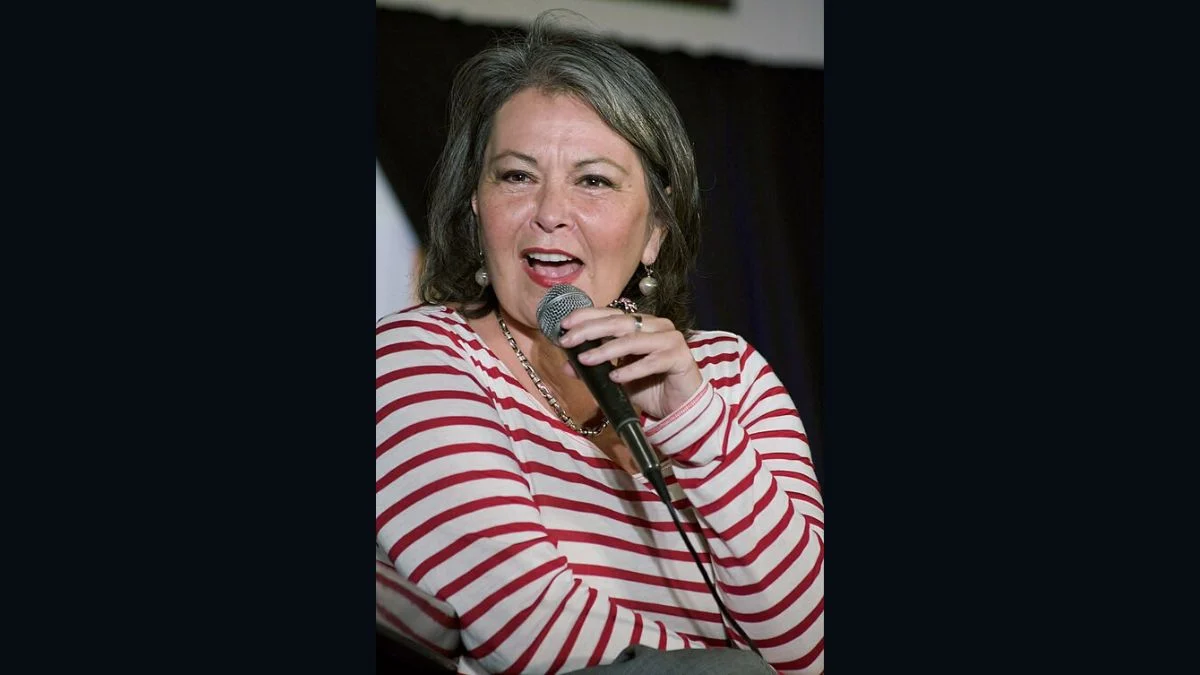 Actress and comedian Roseanne Barr wearing a red-and-white striped long-sleeve top speaking into a microphone.