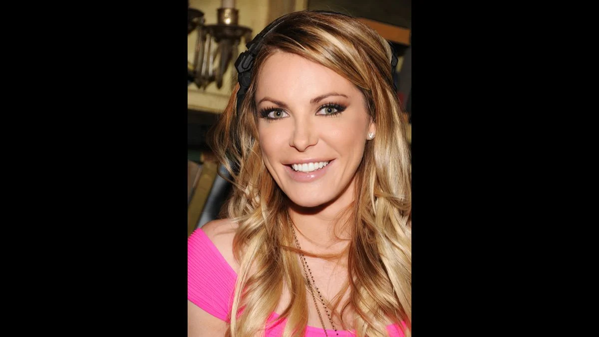 Crystal Harris smiling in a pink off-the-shoulder top with blonde hair