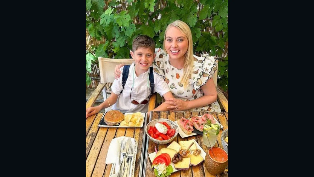 Former Survivor contestant Jaime Dugan sitting at an outdoor dining table with her young son Harper Huffman.