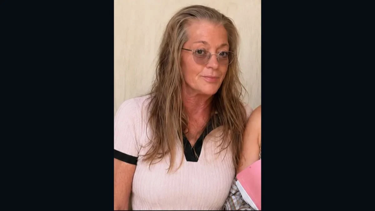 Carla Elaine Johnson, a 64-year-old woman with long blonde hair and glasses, posing for a portrait.