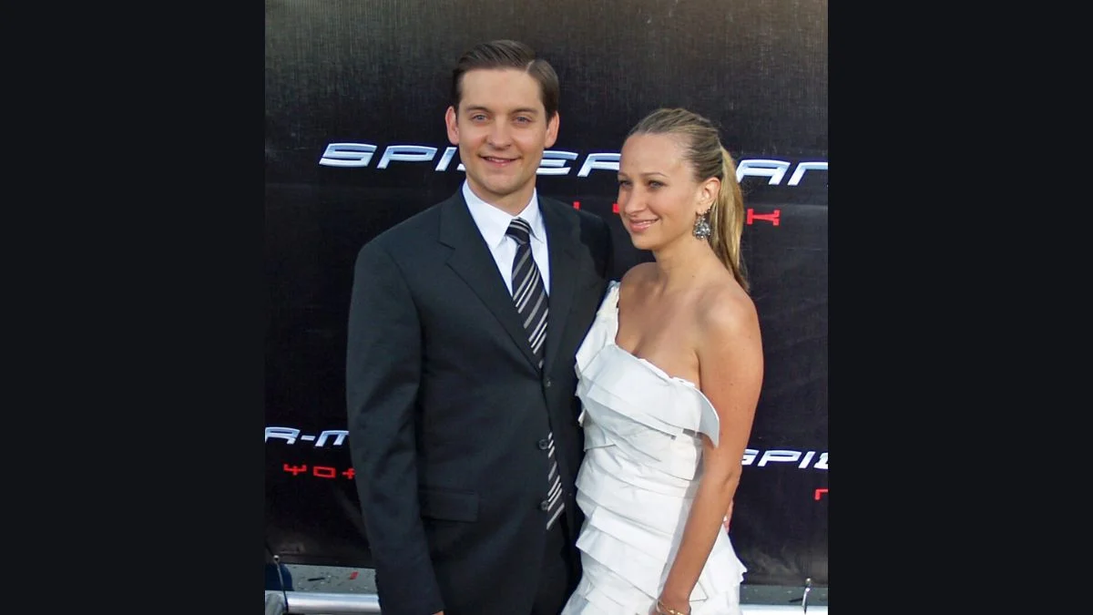 Tobey Maguire standing next to Jennifer Meyer on a premiere red carpet.