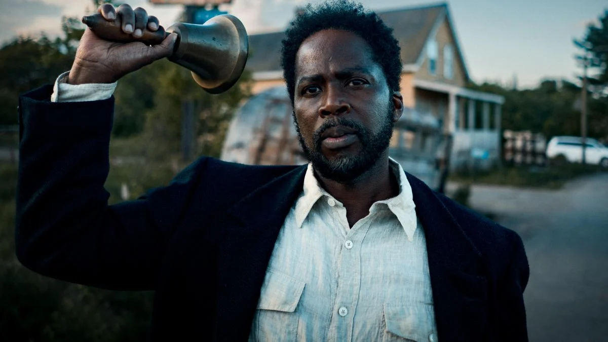 Harold Perrineau as Sheriff Boyd Stevens holding a town bell in a scene from the horror series FROM