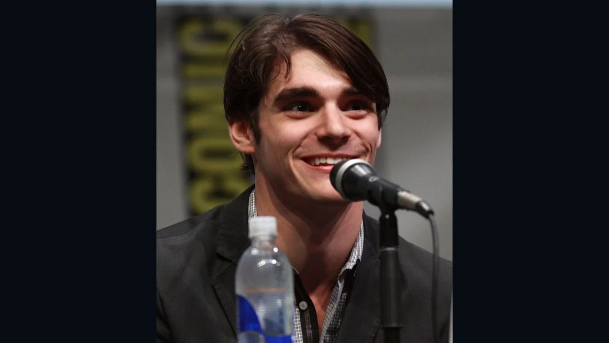 RJ Mitte smiling and speaking into a microphone during a panel discussion at San Diego Comic-Con.