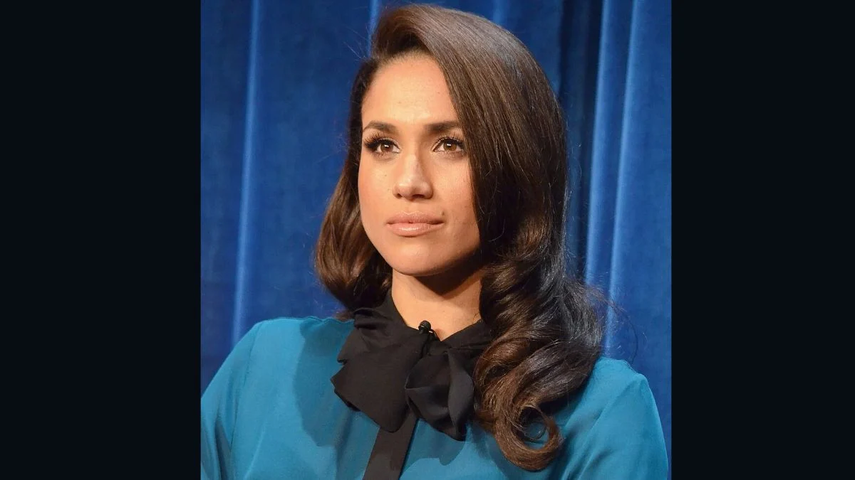 Meghan Markle wearing a teal top with her dark hair styled over her shoulder