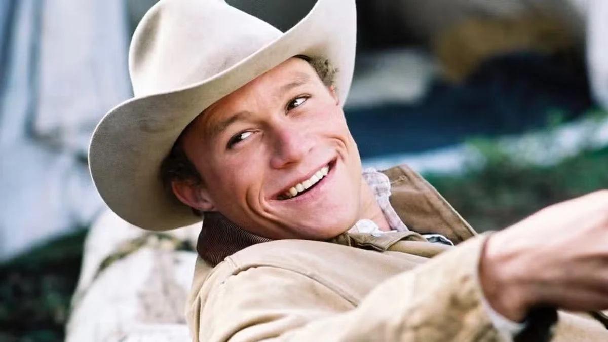 Heath Ledger smiling in a cowboy hat as Ennis Del Mar in Brokeback Mountain