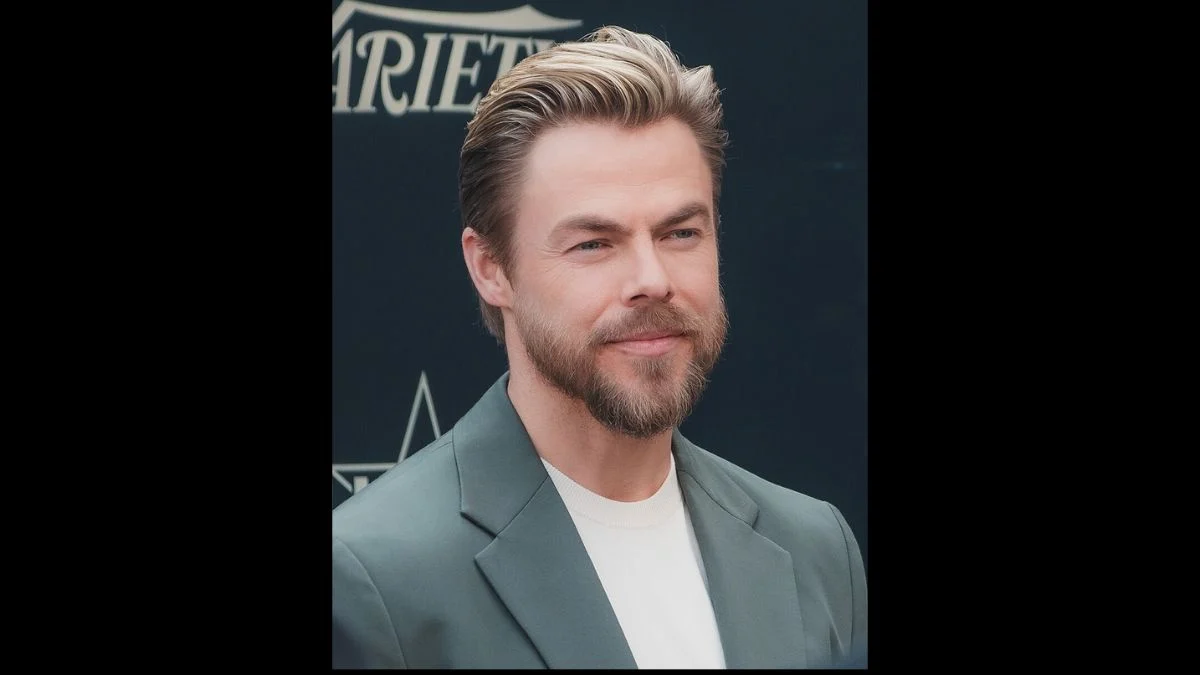 Dancing with the Stars judge Derek Hough smiling on a red carpet event background