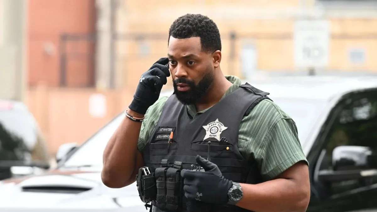 LaRoyce Hawkins as Officer Kevin Atwater wearing a police tactical vest and speaking on his phone outdoors during an investigation.