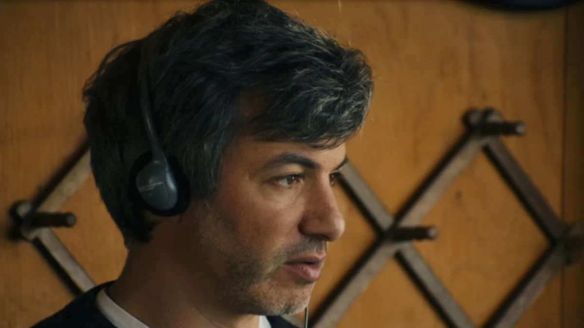Filmmaker Nathan Fielder wearing headphones while listening intently during a documentary production scene