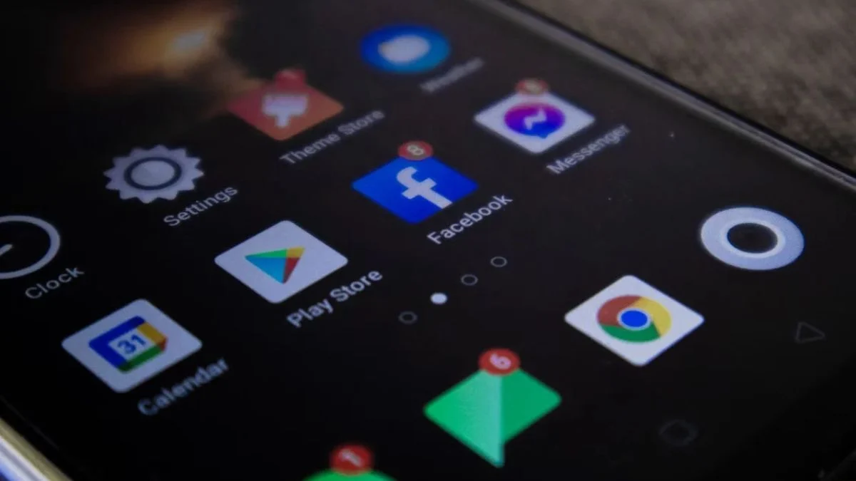 Close-up of a smartphone screen showing app icons including Google Play Store, Facebook, and Chrome