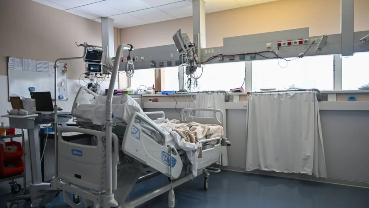 An empty hospital intensive care unit room with advanced medical equipment and monitors.