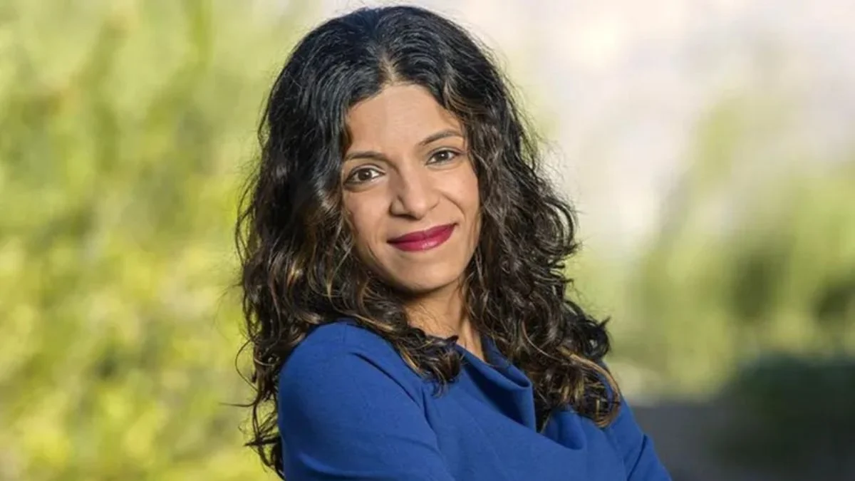 Dr. Rachna Shroff with long dark wavy hair smiling while wearing a blue top outdoors.