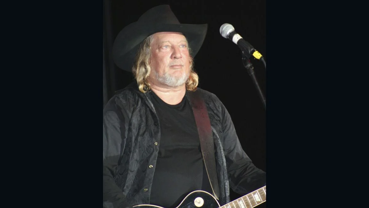 Country music singer John Anderson performing on stage wearing a black cowboy hat and holding an electric guitar