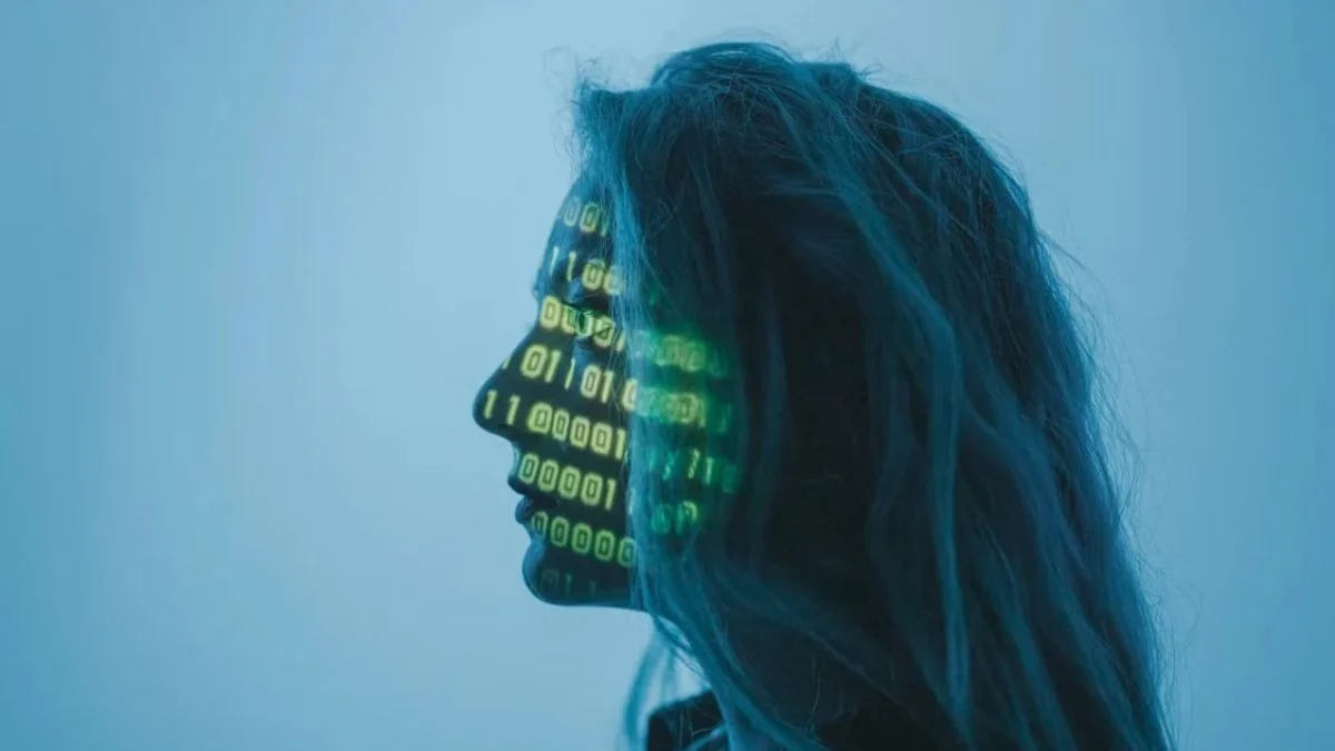 Side profile of a woman with green binary code projected onto her face representing AI technology