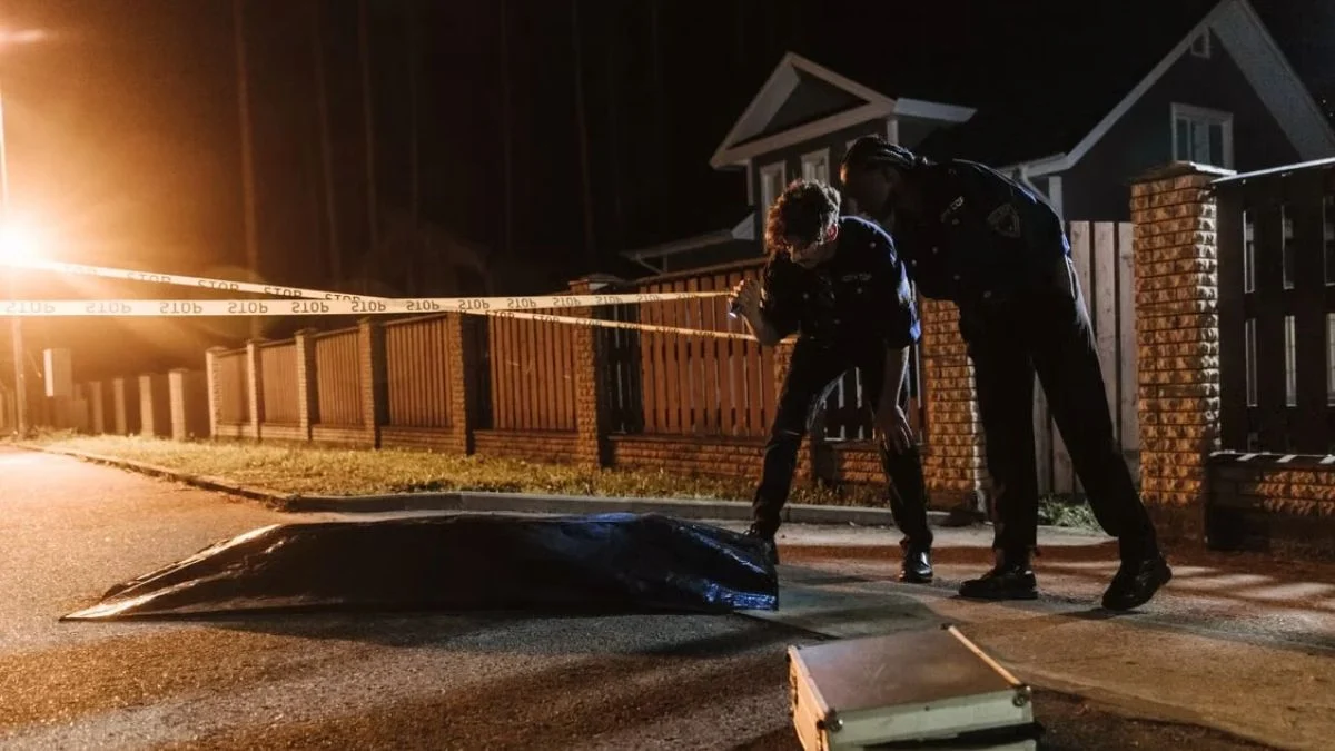 Police officers investigating a crime scene marked with yellow police tape at night